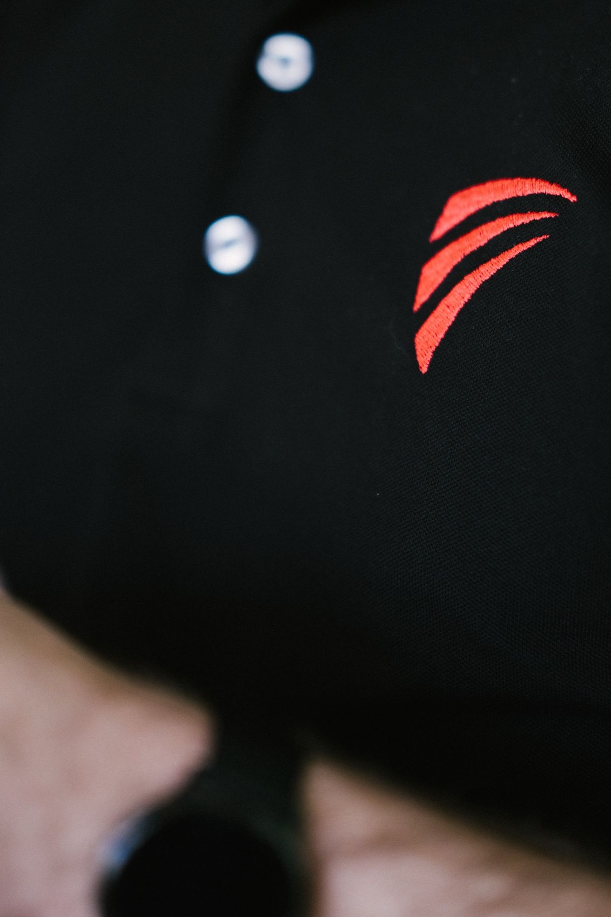 Le symbole rouge brodé sur un polo noir, en gros plan