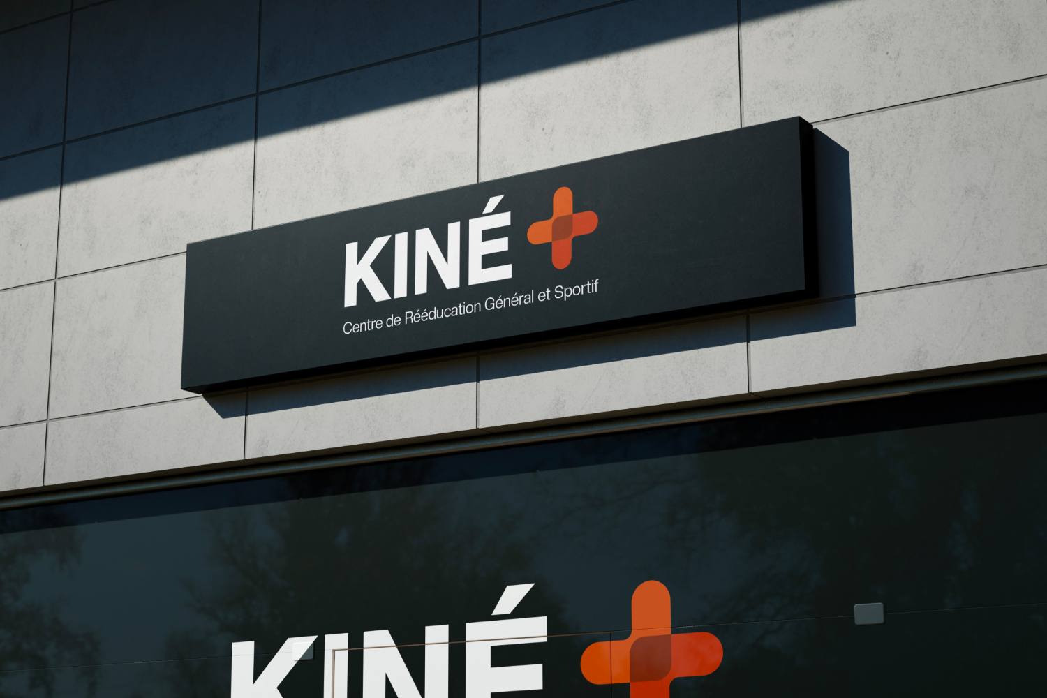 L'enseigne lumineuse KINÉ+ sur la façade du centre : croix orange sur caisson noir