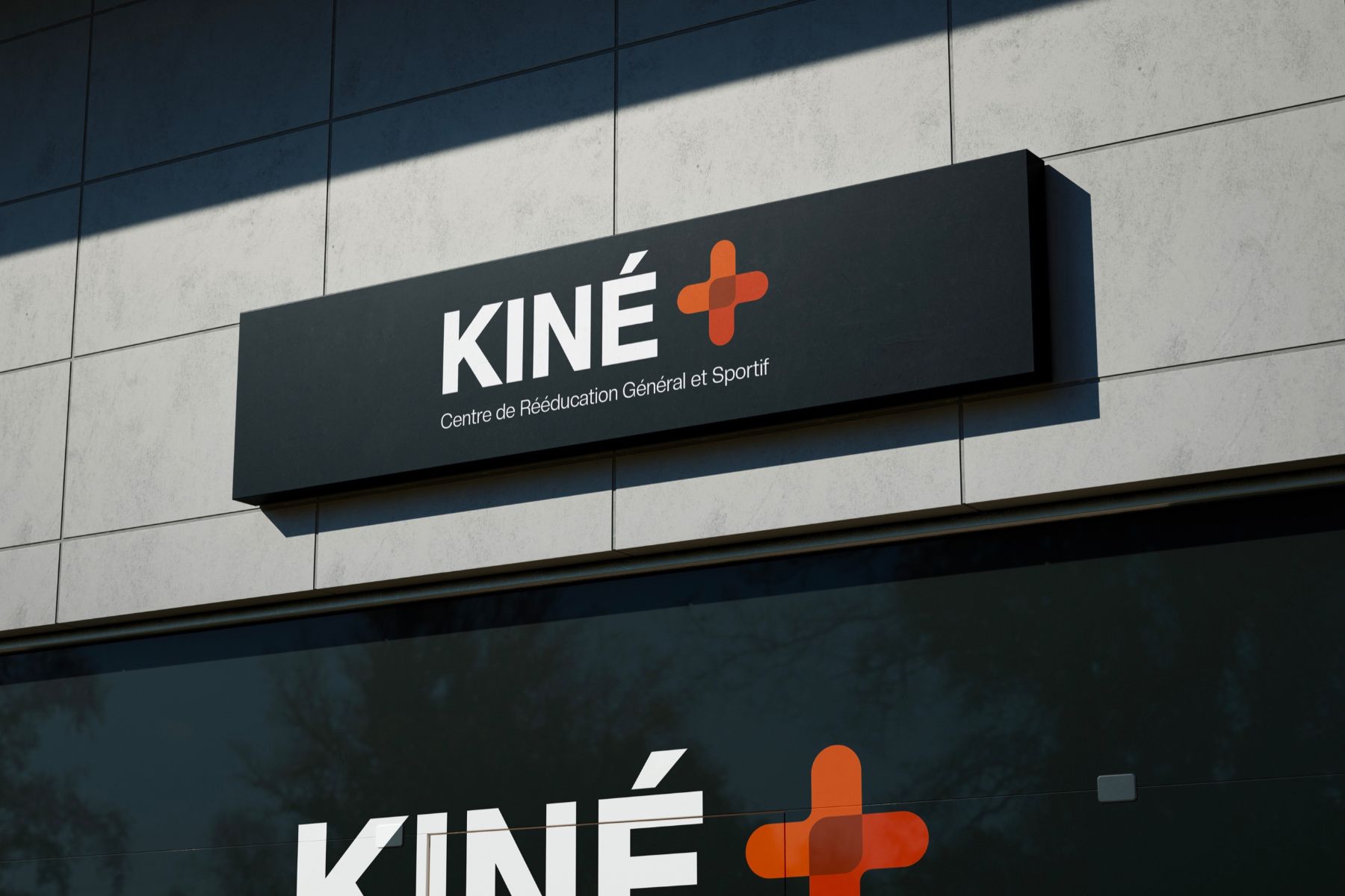 L'enseigne KINÉ+ sur la façade du centre : croix orange sur caisson noir