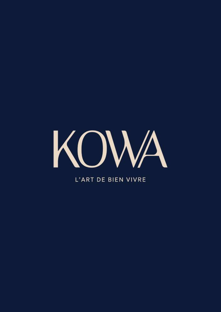 Le monogramme KOWA — une arche dessinée d'un trait — en beige sur bleu nuit